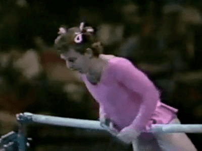 Paul Hunt wearing a pink skirted leotard and ribbon hair tie while performing a gymnastic comedy routine