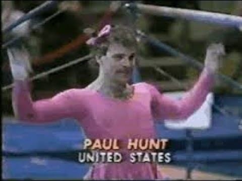 Paul Hunt wearing a pink skirted leotard and ribbon hair tie while performing a gymnastic comedy routine