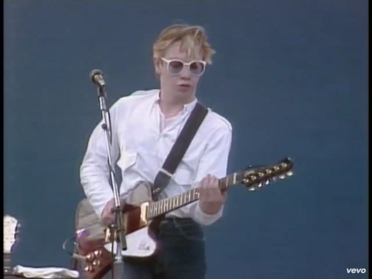 Paul Reynolds playing guitar while wearing white long sleeves and shades