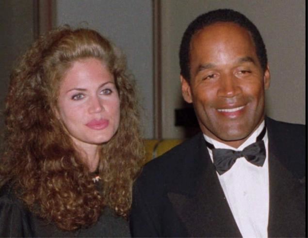 Paula Barbieri wearing a black shirt with OJ Simpson wearing a white shirt, a black coat, and a bow tie