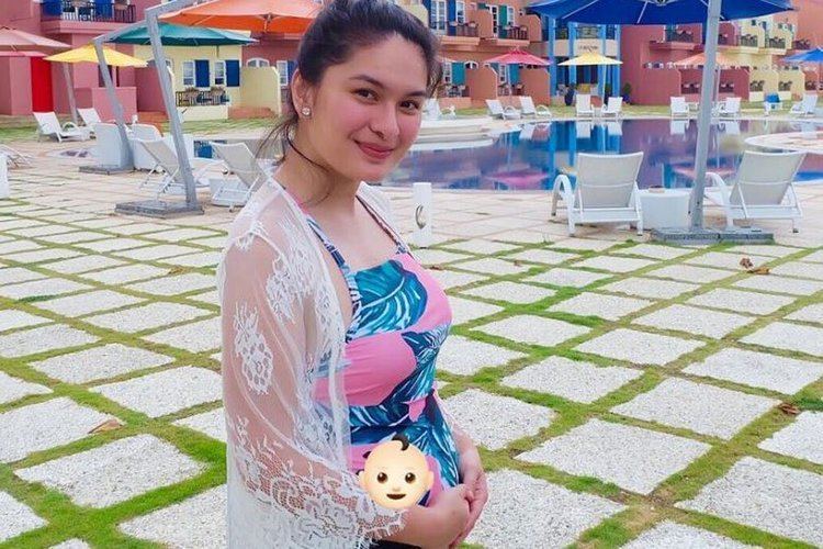 Pauleen Luna wearing earrings, a sexy colorful dress with white lace while holding her baby bump.