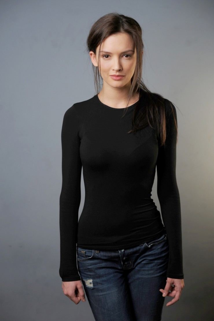 Paulina Andreeva with a tight-lipped smile while wearing a black long sleeve blouse and denim pants