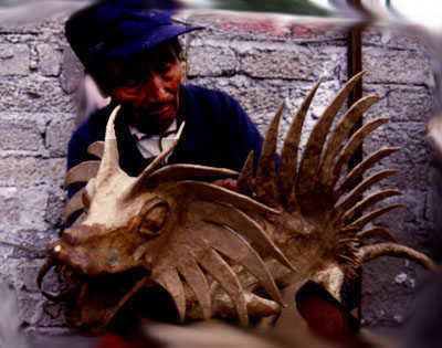 Pedro Linares sitting and wearing a cap while holding an Alebrijes  Dragon