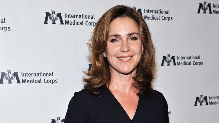 Peri Gilpin smiling, with wavy hair and wearing a black shirt.