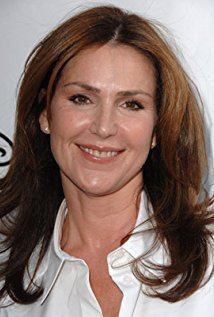 Peri Gilpin smiling, with wavy hair and wearing a white polo shirt.