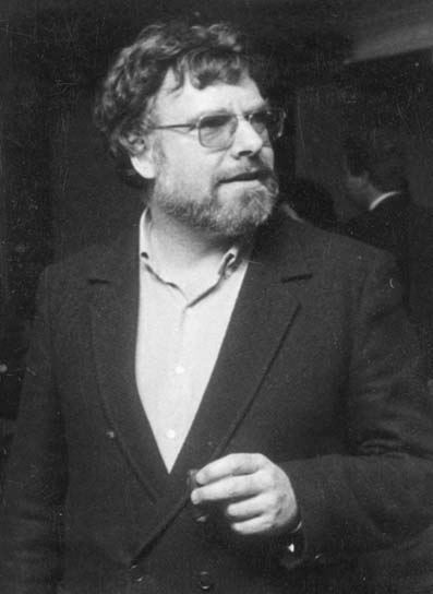 Peter Fleischmann with beard and mustache, wearing eyeglasses, and a black coat over white long sleeves.