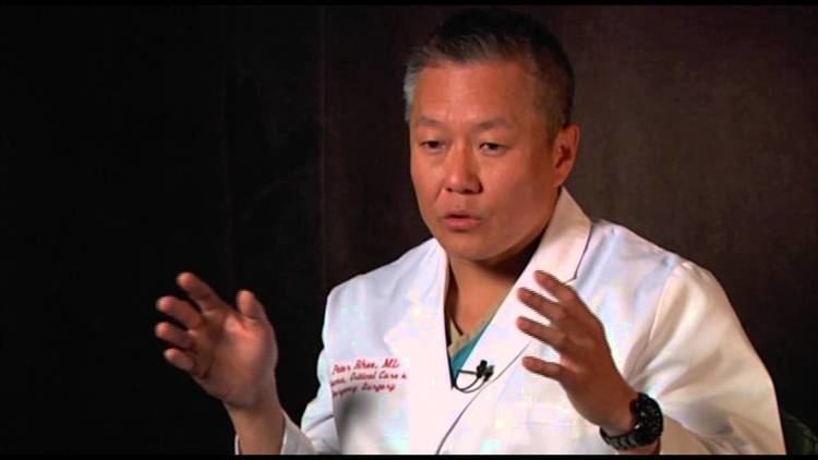Peter M. Rhee talking in an interview and wearing a doctors gown.