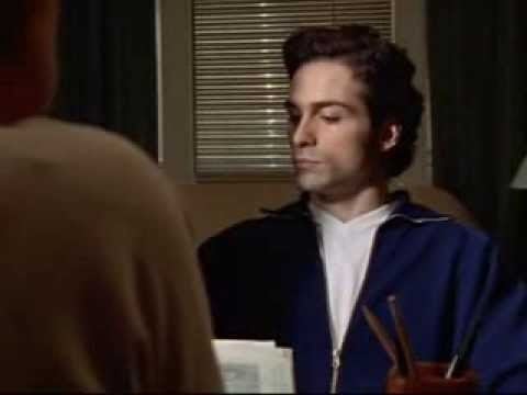 Peter Schibetta wearing a blue jacket and white shirt in a scene from the 1997 tv series Oz