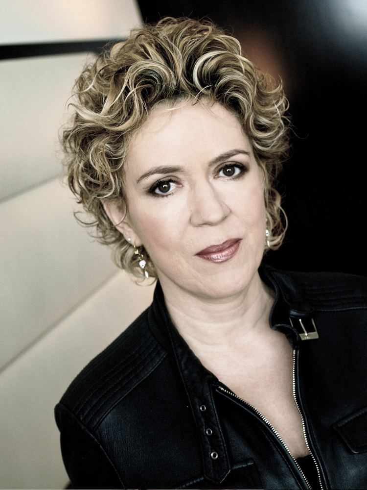 Petra Reski posing with her short, curly hair and wearing a black leather jacket.