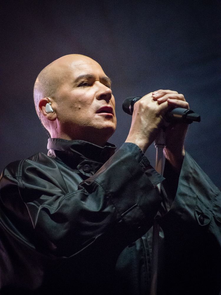 Philip Oakey wearing an all-black long-sleeved shirt while singing