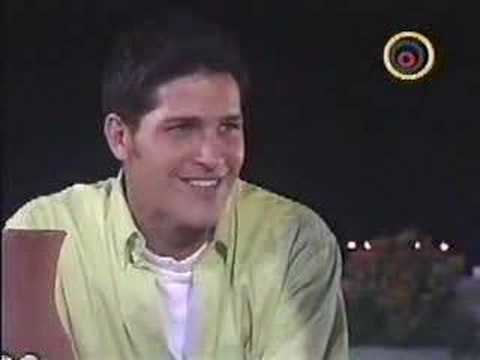 Roberto Cano as Pablo Herminio smiling while wearing a white shirt under yellow sleeves in a scene from the 2000 Telenovela "Pobre Pablo"