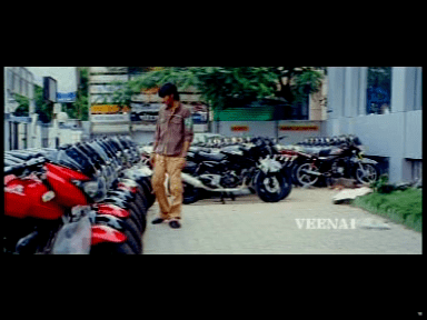 Dhanush looking at the motorcycle in a movie scene from Polladhavan (2007 film)