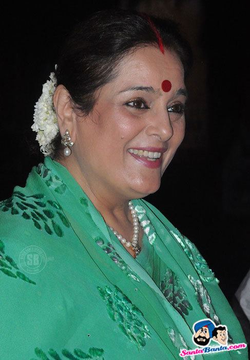 Poonam Sinha smiling while wearing green dress, earrings and necklace