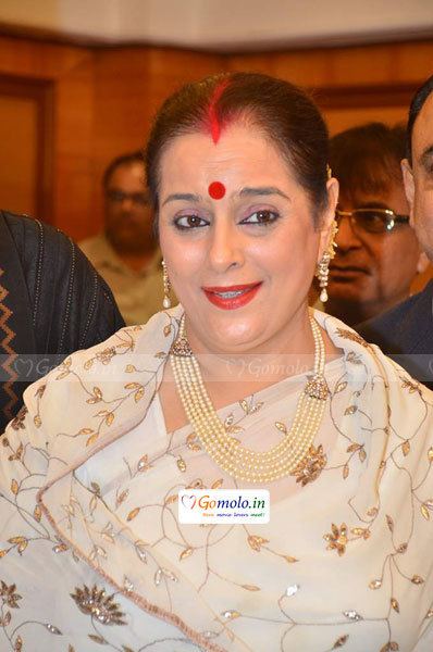 Poonam Sinha smiling while wearing brown and cream dress and jewelries