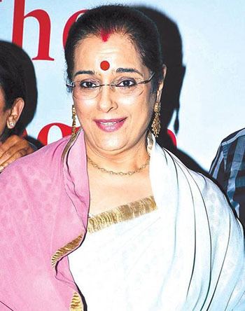 Poonam Sinha smiling while wearing white and pink dress, eyeglasses, earrings and necklace