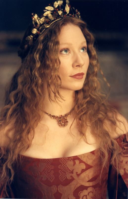 Lynn Collins looking serious in an off-shoulder dress with her blonde hair down and adorned with a crown and necklace as Portia in Merchant of Venice