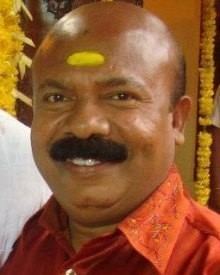 Pradeep Kottayam smiling with a yellow Tika on his forehead and wearing an orange collared shirt