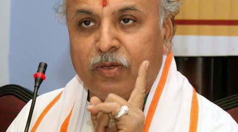 Pravin Togadia speaking while pointing his finger and wearing a white shirt and white and orange sash