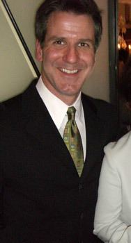 Prentis Cobb "Rusty" Hale III is smiling, has black hair, wearing white long sleeves, a green necktie under a black suit.