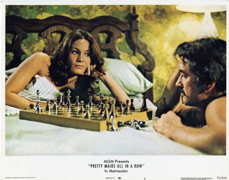 Barbara Leigh lying on a bed while looking at Rock Hudson playing chess in a movie scene from Pretty Maids, a 1971 American sexploitation film.