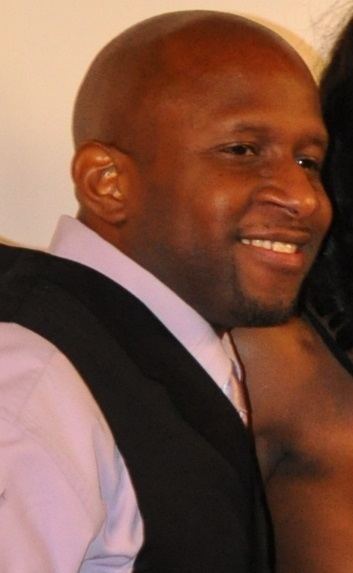 Prince Yahshua smiling while wearing black vest and pink long sleeves