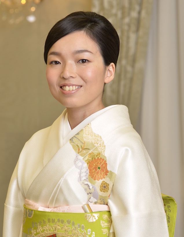 Princess Akiko of Mikasa smiling and wearing an off-white and green kimono with a floral design.