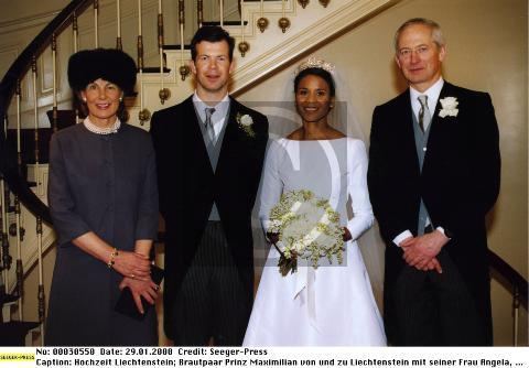 Marie Kinsky, Prince Maximilian, Princess Angela, and Hans-Adam II, Prince of Liechtenstein (left to right) are smiling at the wedding ceremony. Princess Angela is holding a bouquet of flowers and wearing a white long-sleeve gown, white veil, and crown while Prince Maximilian is wearing dark gray pants and white long sleeve under a gray necktie, gray vest, and black coat
