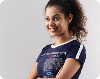 Karishma Randhawa as Princess Dollie Suri, smiling while wearing a white and blue printed t-shirt