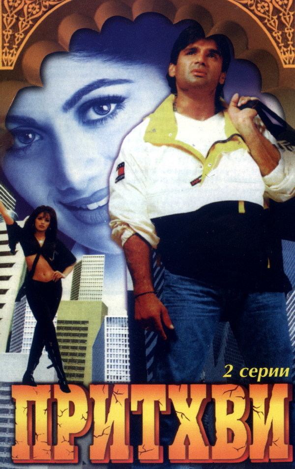 The movie poster of Prithvi 1997, at the back, Shilpa Shetty is smiling, has black hair and city buildings, on the left side, Shilpa Shetty is serious, standing, legs crossed right foot forward, has long black hair, wearing a black top with sleeves, black bag, black pants and black boots, at the right side, Suniel Shetty is serious, standing, right hand down while left hand on his shoulder holding a black bag, has black hair, shaved beard and mustache, wearing black rubber band a black and white jacket with yellow collar, blue denim pants.