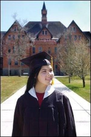 Promethea Pythaitha smiling while looking afar and wearing a black academic dress