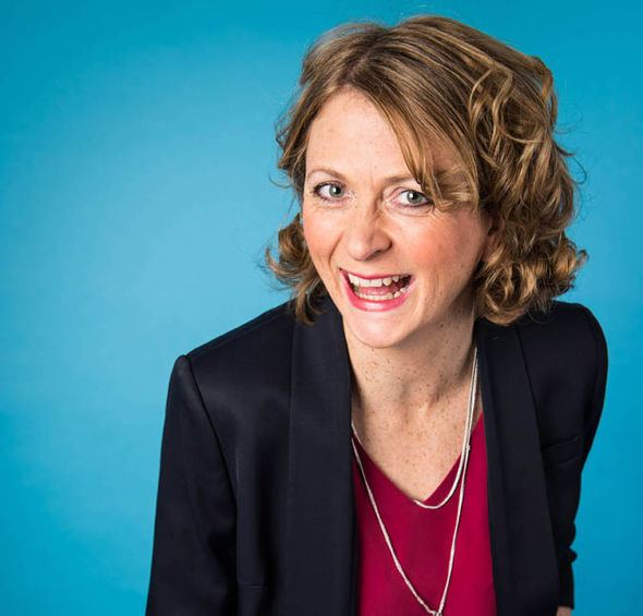 Smiling Rachel Burden wearing a black suit in sky blue background