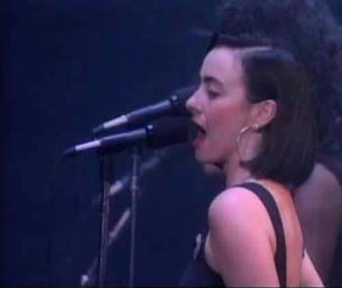 Rachel Fury singing while wearing a black sleeveless top and earrings