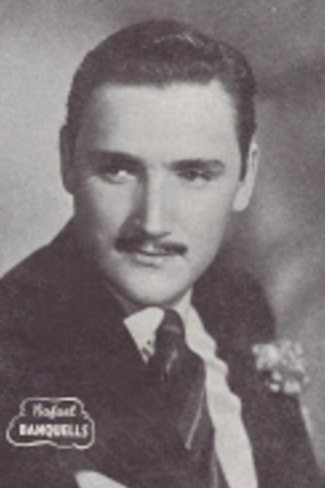 Rafael Banquells with mustache while wearing a black coat, white long sleeves, and striped necktie