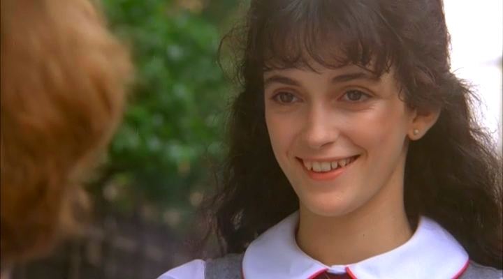 Rainbow Harvest smiling while wearing a blouse with a white collar in a movie scene from the 1984 film Old Enough