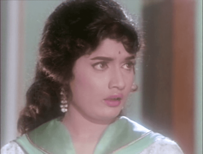 Rajshree with a sad face, with curly hair, wearing earrings and an avocado green top.