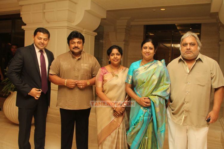 Ramkumar Ganesan wearing a polo shirt and white pants together with two ladies wearing a colorful dress and two gentlemen wearing a black suit and a brown polo.