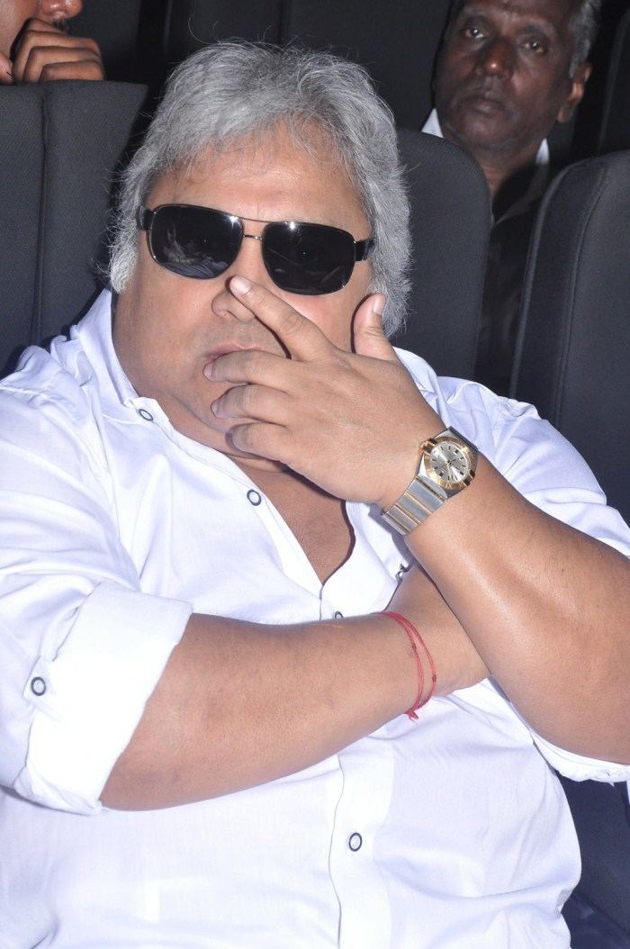 Ramkumar Ganesan with white hair, wearing sunglasses, a white polo shirt, and a watch with a man on his back.