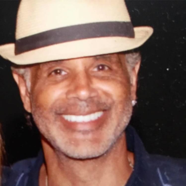 Ramon Hervey II smiling while wearing a black and cream hat