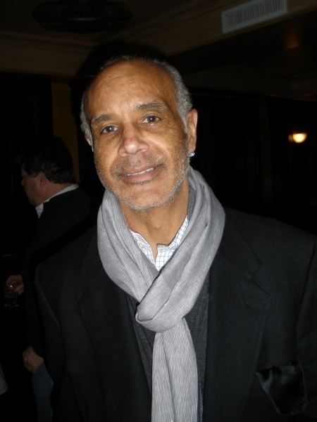 Ramon Hervey II smiling while wearing a black coat and gray scarf