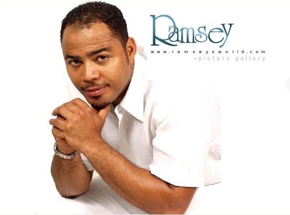 Ramsey Nouah's hands on his chin while wearing white polo