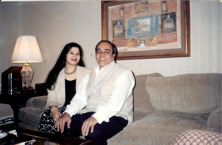 Rangarajan Kumaramangalam smiling and wearing white long sleeves together with his wife Kitty Kumaramangalam smiling, with long black hair, wearing a blazer, and a black shirt.