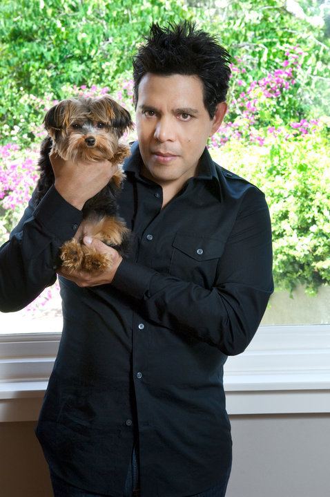 Raul Julia-Levy carrying a brown Shih Tzu dog while wearing black long sleeves