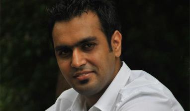 Ravinder Singh smiling while wearing a white long sleeves