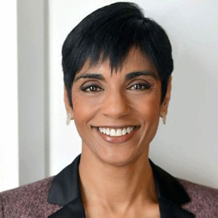 Reeta Chakrabarti smiling while wearing a black and brown blazer
