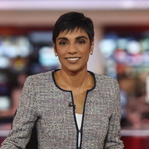 Reeta Chakrabarti smiling while wearing a black and gray blazer and white inner blouse