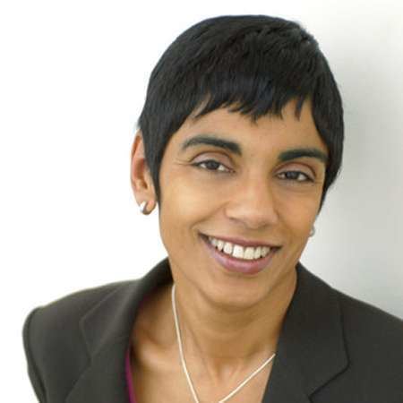 Reeta Chakrabarti smiling while wearing a black blazer, necklace, and earrings