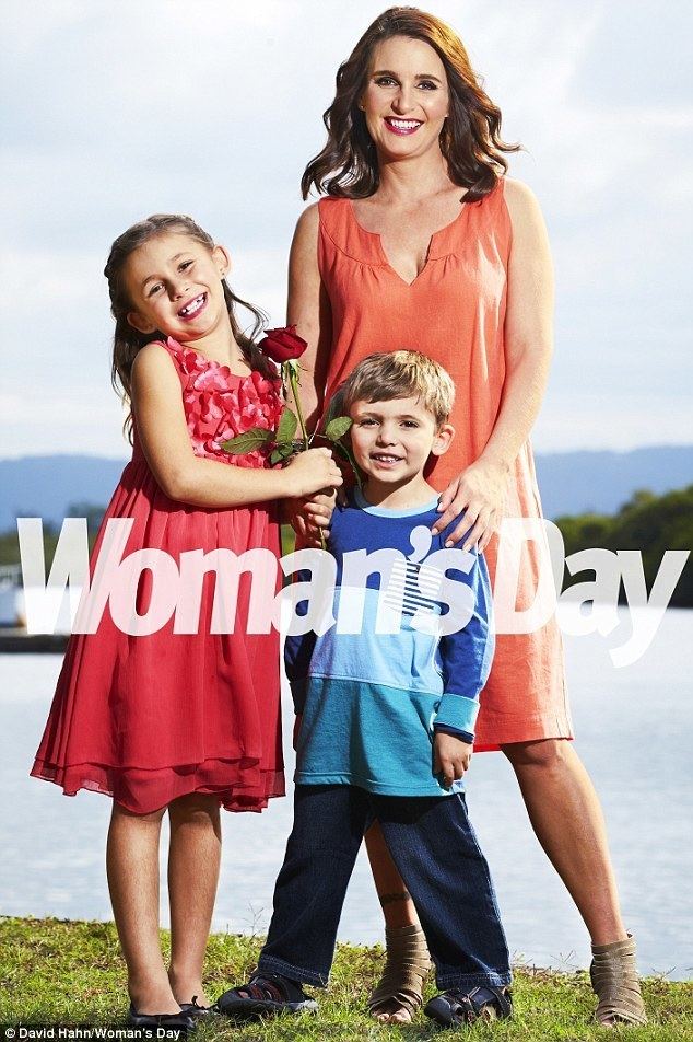 On a Woman’s Day, the magazine cover is Mia (left) smiling, has blonde hair, both hands holding a rose, and wearing a red dress and black shoes. In the middle is Lucas smiling, has blonde hair, wearing a blue long sleeve shirt with different shades of blue, jeans, and black slippers. Regina Bird (right) is smiling, has brown hair, a tattoo on her right leg, and both hands holding her son (Lucas) wearing an orange cleavage showing dress and gray sandals.
