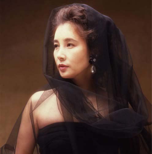 Reiko Ohara looking afar while wearing a black dress and black net on her head