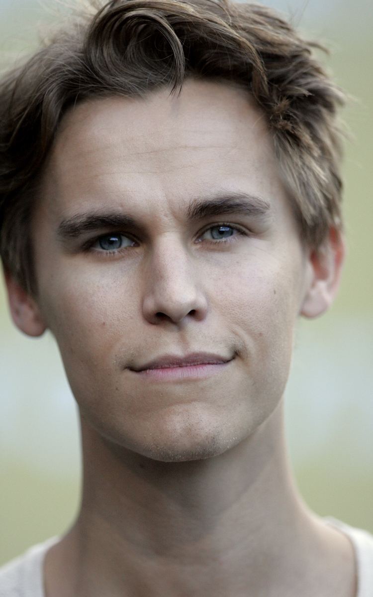 Rhys Wakefield smiling with his blonde hair wearing a white shirt