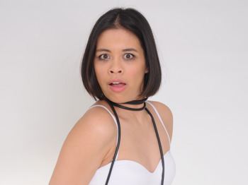 Ria Lina looking shocked while wearing a white sleeveless shirt